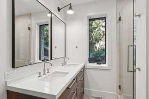 Full bath with plenty of natural light, a shower stall, and double vanity