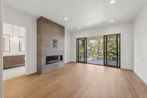 Unfurnished living room featuring light wood-style floors, a tiled fireplace, and recessed lighting