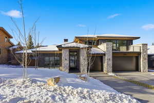 View of front of home featuring concrete driveway, a garage, a chimney, and stone siding