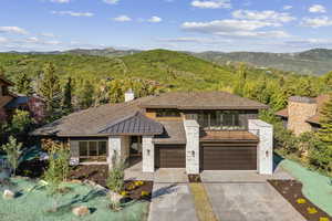 Prairie-style home with an attached garage, a mountain view, driveway, and a chimney