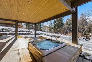 Snow covered patio featuring a hot tub and a patio