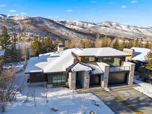 View of front facade featuring a mountain view, a chimney, driveway, a garage, and stone siding