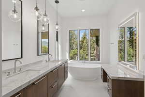 Bathroom featuring a freestanding bath, double vanity, recessed lighting, and light tile patterned floors