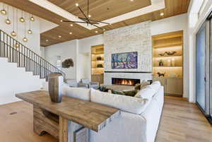 Living area with built in shelves, wooden ceiling, a fireplace, light wood-type flooring, and stairway