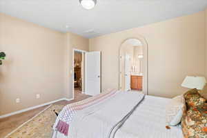 Bedroom featuring arched walkways, carpet flooring, and ensuite bathroom