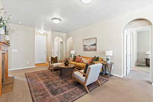 Living room with arched walkways, a fireplace, and light carpet