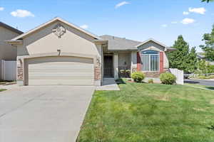 Single story home with stone siding, a garage, stucco siding, and concrete driveway