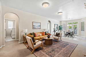 Living room featuring light colored carpet, arched walkways, and light tile patterned flooring