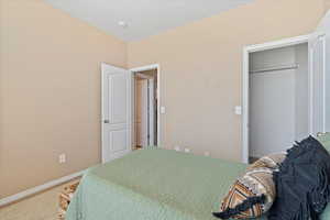 Carpeted bedroom with baseboards and a closet