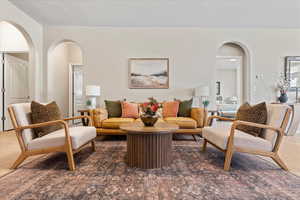 Carpeted living room featuring arched walkways