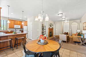 Dining space with a fireplace with flush hearth, light tile patterned flooring, a textured ceiling, light carpet, and recessed lighting