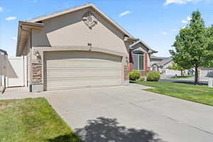 Single story home featuring stone siding, an attached garage, driveway, and stucco siding