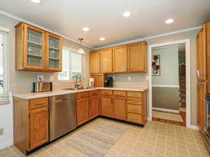 Kitchen featuring decorative light fixtures, light countertops, appliances with stainless steel finishes, ornamental molding, and recessed lighting