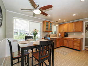 Kitchen featuring light countertops, decorative light fixtures, crown molding, dishwasher, and brown cabinets