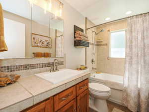 Bathroom with shower / bath combo with shower curtain, vanity, tasteful backsplash, recessed lighting, and dark tile patterned flooring