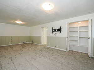 Bonus area featuring a wainscoted wall, a textured ceiling, and carpet floors