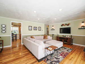 Living area featuring ornamental molding, light wood finished floors, a textured ceiling, and recessed lighting