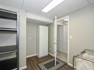 Interior space with a drop ceiling and dark wood-style floors