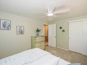 Bedroom with light carpet, ceiling fan, and a closet