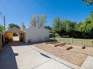 View of patio / terrace featuring a vegetable garden, concrete driveway, and a detached carport