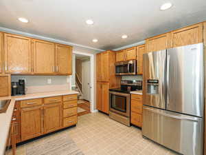 Kitchen featuring appliances with stainless steel finishes, light countertops, recessed lighting, and crown molding