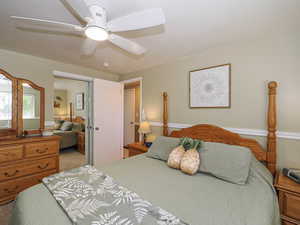Bedroom with ceiling fan, light colored carpet, and a closet