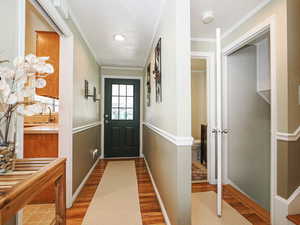 Doorway featuring wood finished floors and crown molding