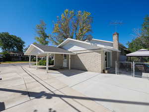 Single story home with a gate, a chimney, brick siding, and a gazebo