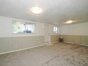 Family room or bedroom featuring wainscoting, a textured ceiling, and carpet flooring