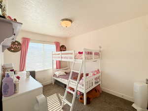 Bedroom featuring dark carpet and a textured ceiling