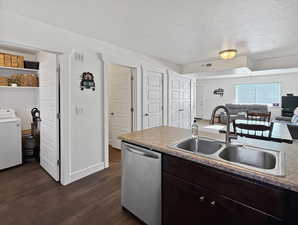 Kitchen with dark brown cabinetry, dishwasher, washer / clothes dryer, dark wood-style floors, and open floor plan