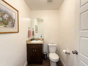Half bath featuring vanity, dark wood-style floors, and a textured ceiling