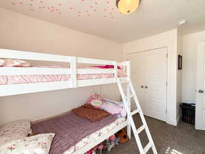 Bedroom featuring dark colored carpet, a closet, and a textured ceiling