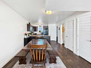 Dining space with a textured ceiling and dark wood-type flooring