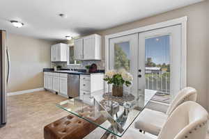 Kitchen featuring tasteful backsplash, white cabinetry, french doors, and appliances with stainless steel finishes