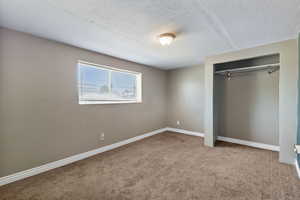 Unfurnished bedroom featuring light carpet, a closet, and a textured ceiling