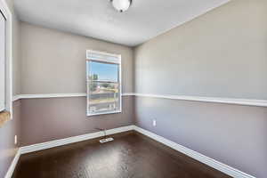 Unfurnished room with dark wood-style floors and a textured ceiling