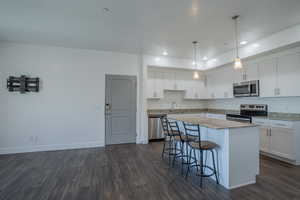 Kitchen with recessed lighting, white cabinetry, a kitchen breakfast bar, decorative light fixtures, and dark wood finished floors