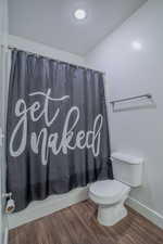 Bathroom with dark wood-style floors, shower / tub combo with curtain, and a textured ceiling