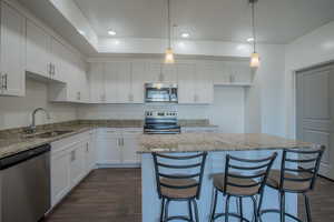 Kitchen featuring white cabinetry, appliances with stainless steel finishes, hanging light fixtures, recessed lighting, and a kitchen breakfast bar