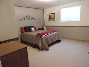 Bedroom with light colored carpet and a textured ceiling