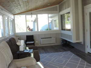 Sunroom / solarium featuring wood finished floors, lofted ceiling, wood ceiling, and a wall mounted AC