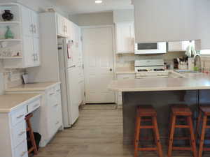 Kitchen with open shelves, light countertops, white cabinets, backsplash, and white appliances