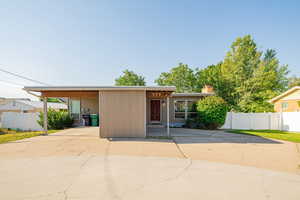 View of front of house with driveway, a carport, and a chimney