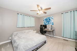 Bedroom featuring light carpet, a ceiling fan, and an office area