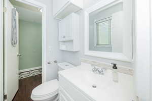 Half bathroom featuring vanity, dark wood-type flooring, and decorative backsplash