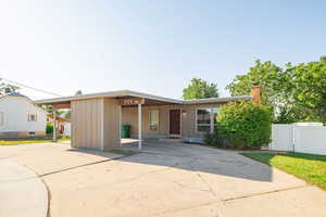 View of front of home featuring a chimney, an attached carport, concrete driveway, and board and batten siding