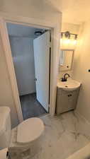 Half bath with vanity, a textured ceiling, and light marble finish floors