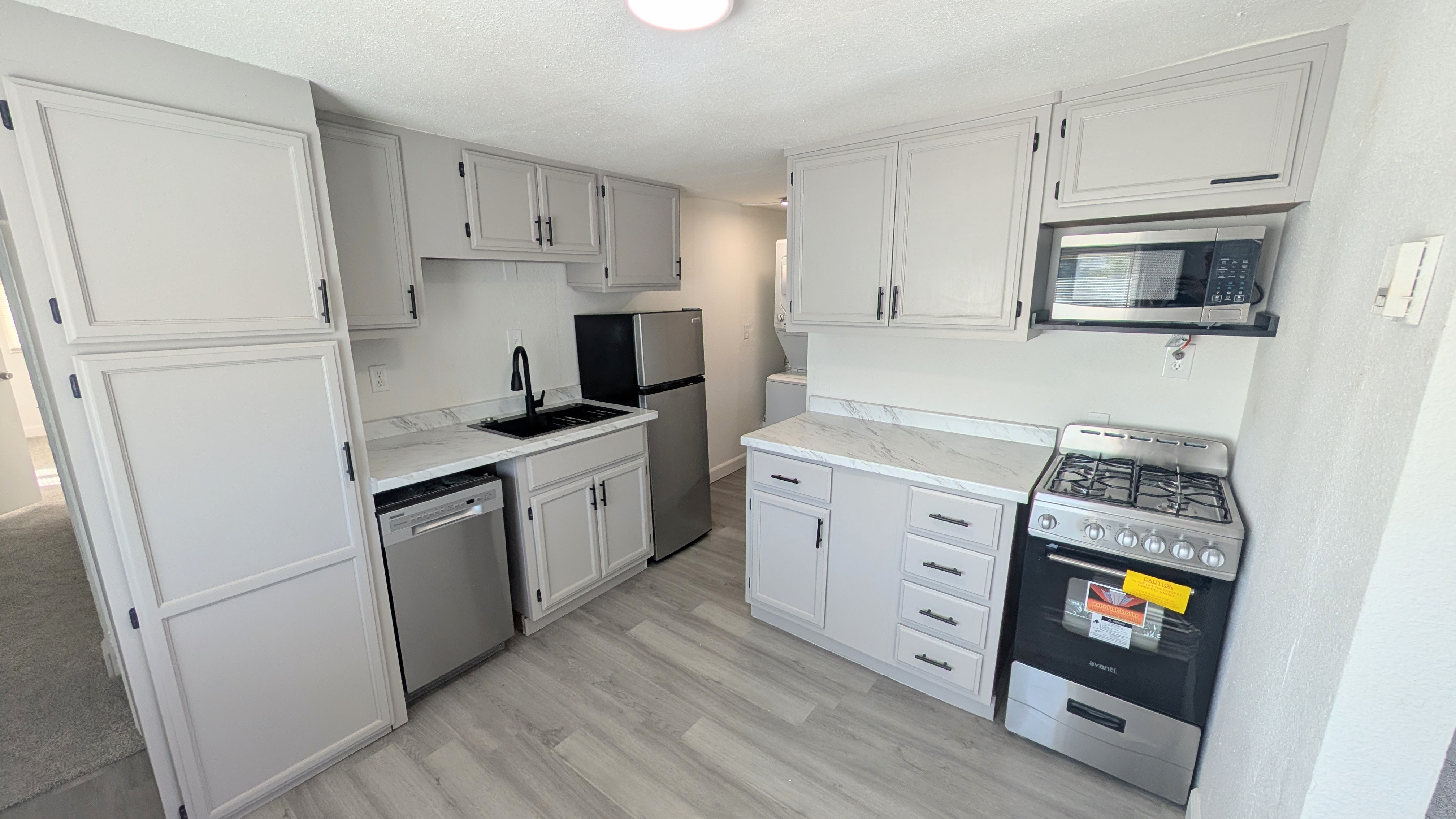 Kitchen with appliances with stainless steel finishes, light countertops, light wood-style floors, and a textured ceiling