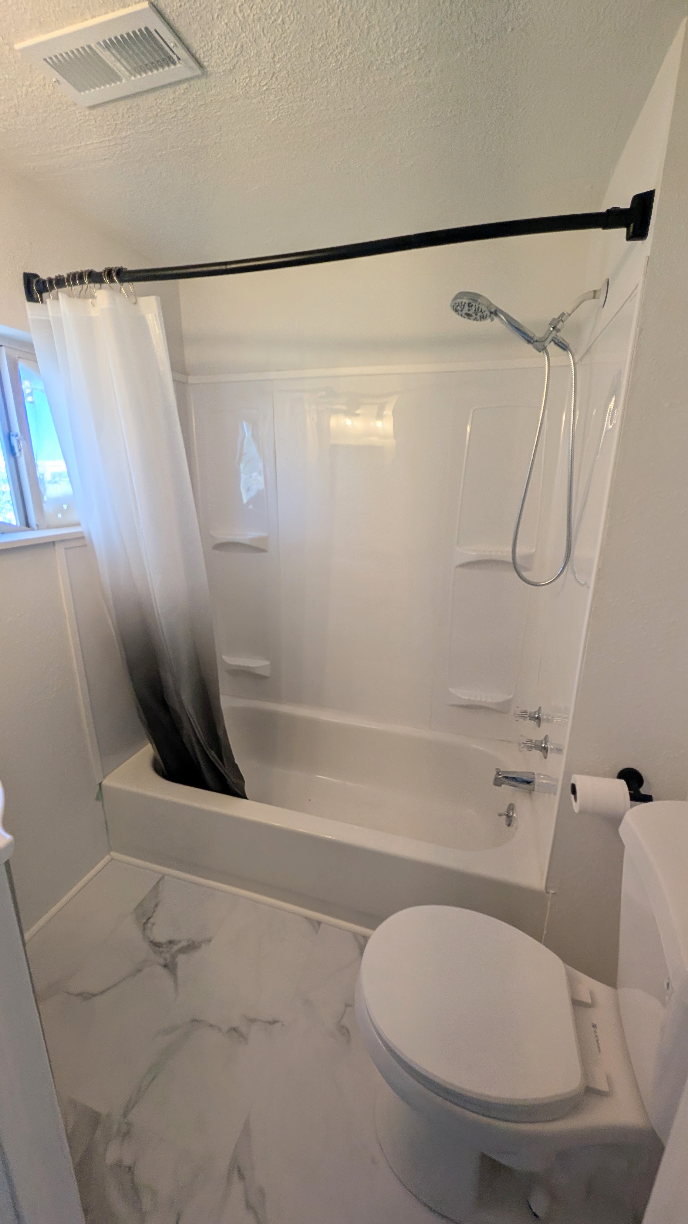 Full bath featuring shower / tub combo, a textured ceiling, marble look tiles, and vanity